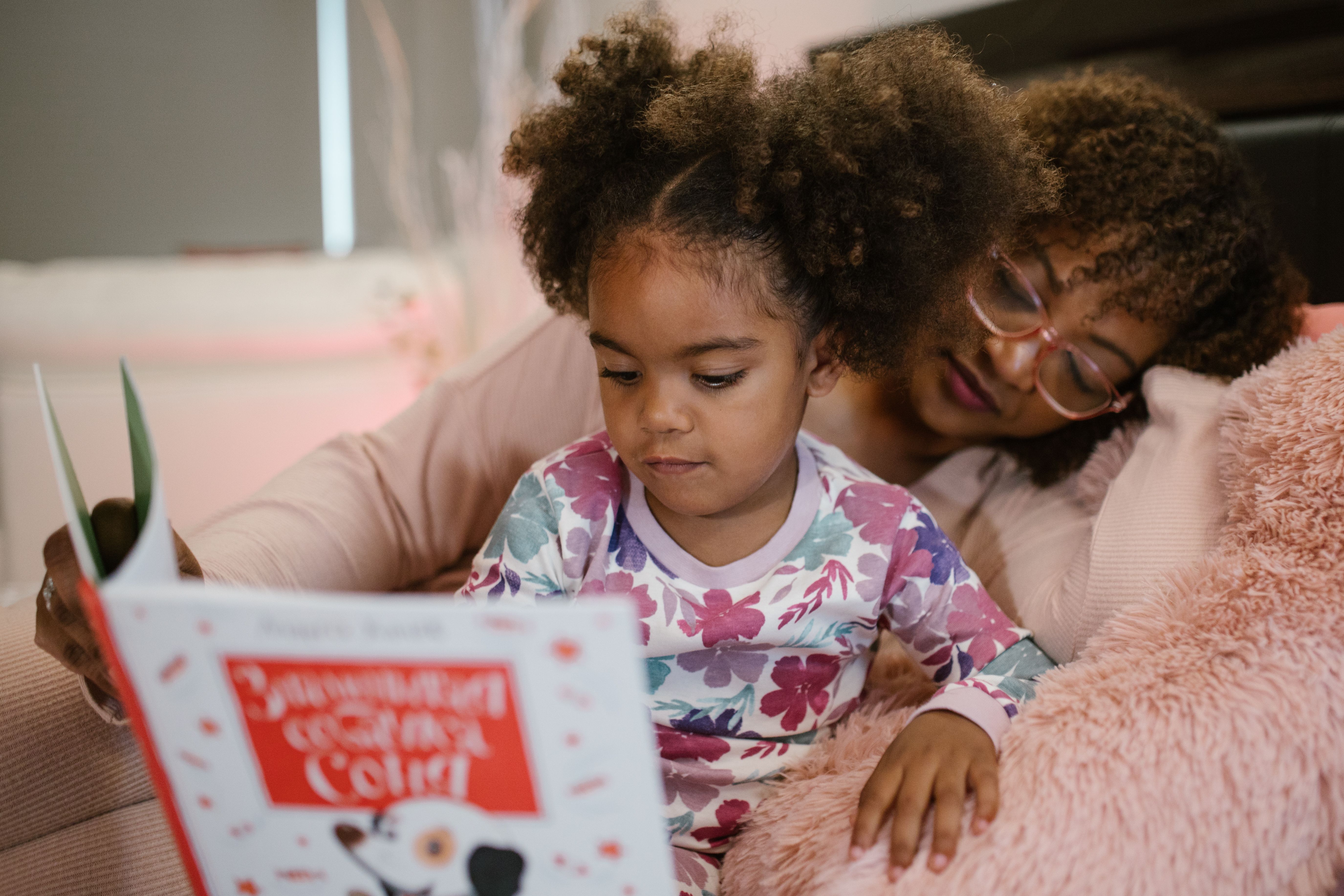 An adult and a child reading a book together.